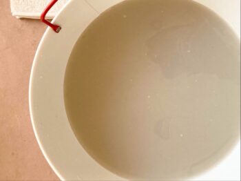 取っ手が赤い白の琺瑯の桶に入ったクレイ足湯用のお湯