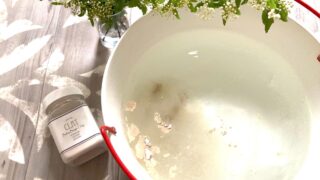 お湯が入った琺瑯の桶とベビーベージュクレイとコデマリ