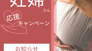 お腹を抱えた白い洋服を着た妊婦さん