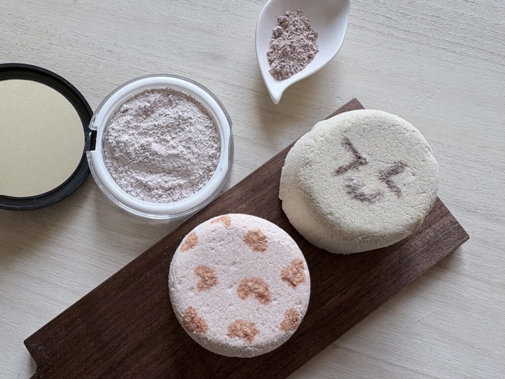 丸いクレイバスボムが２つ並んでいる。コンパクトに入ったクレイパウダーが置いてある。